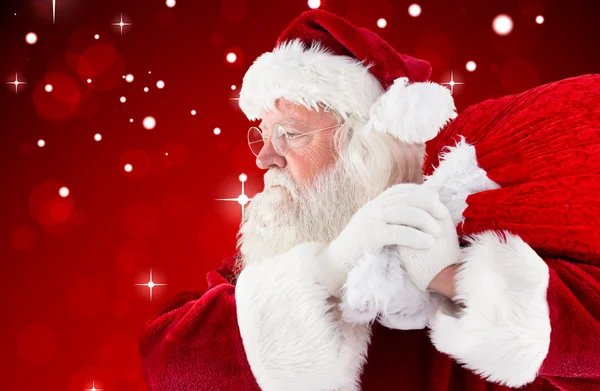 Композитное изображение Санта-Клауса, несущего мешок — стоковое фото