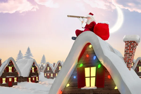 Composite image of santa sitting on roof of cottage — Stock Photo, Image