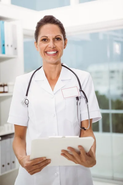 Female doctor holding clipboard in medical office — Stock Photo, Image