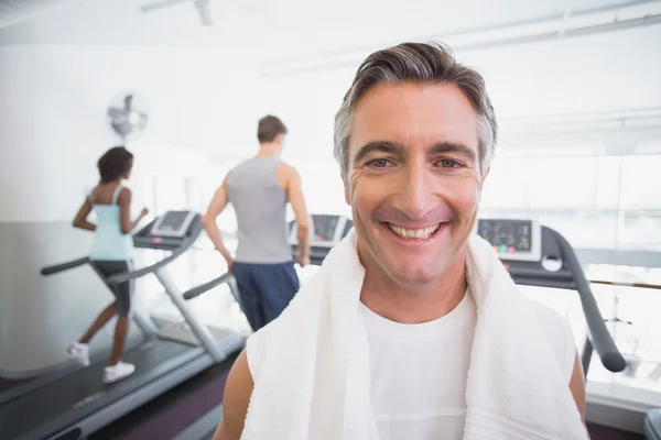 Fit homem sorrindo para a câmera ao lado esteiras — Fotografia de Stock