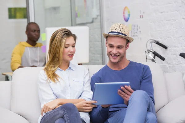 Casual collega's met digitale tablet op Bank in office — Stockfoto