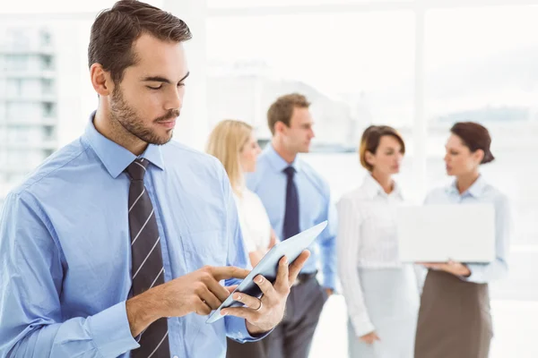 Businessman using digital tablet with colleagues behind — Stock Photo, Image