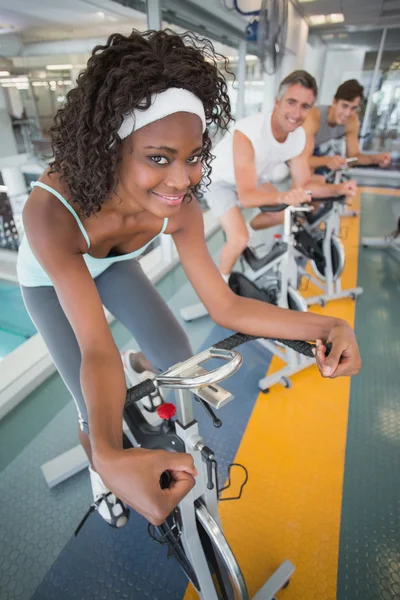 Three fit people working out on exercise bikes — Stock Photo, Image