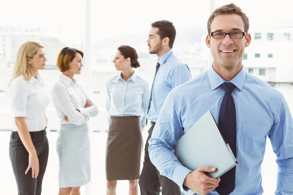 Empresário sorridente com colegas por trás — Fotografia de Stock