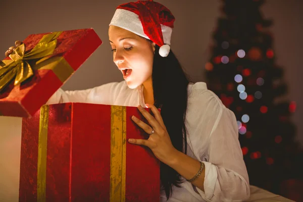 Feestelijke brunette openen een gloeiende kerstcadeau — Stockfoto