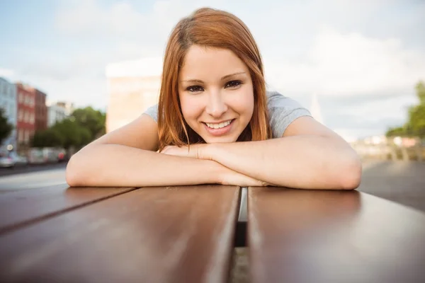 Portrait of a smiling redhead lying on bench — Stock Photo, Image