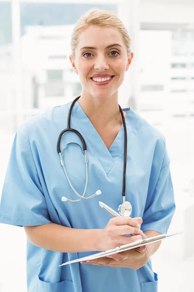 Retrato de una doctora sonriente escribiendo en el portapapeles —  Fotos de Stock