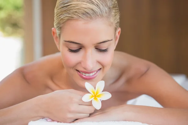 Kvinna anläggning blomma på massagebänk — Stockfoto