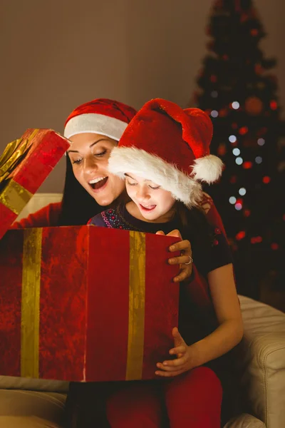 Festliche Mutter und Tochter öffnen ein leuchtendes Weihnachtsgeschenk — Stockfoto
