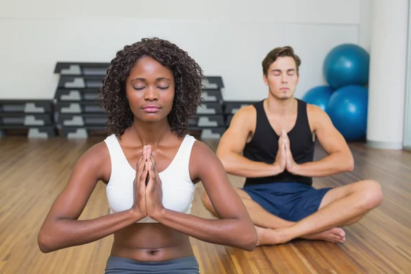 Adatta coppia seduta in posa di loto in palestra — Foto Stock