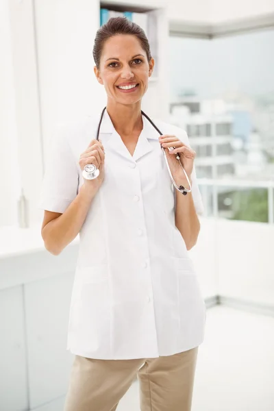 Улыбающаяся женщина-врач со стетоскопом в медицинском кабинете — стоковое фото