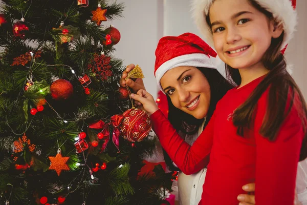 Moeder en dochter opknoping kerstversiering op boom — Stockfoto