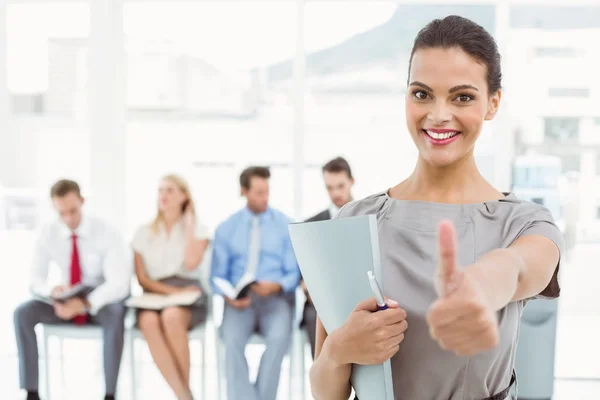 Businesspeople looking at file against people waiting for interview — Stock Photo, Image