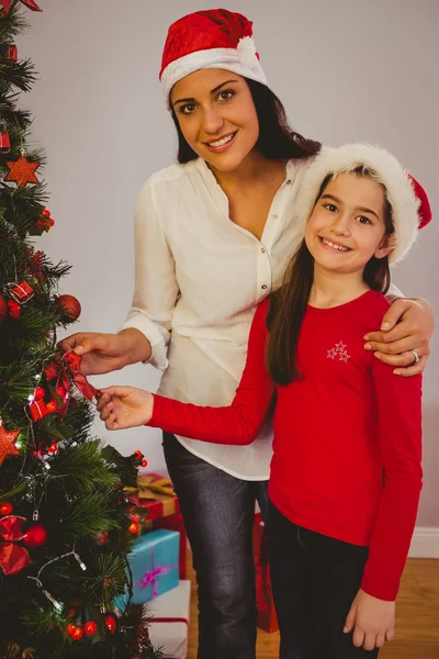 Mutter und Tochter hängen Weihnachtsschmuck an Baum — Stockfoto