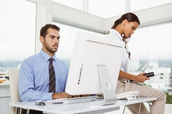 Affärsman med dator medan kvinnan på samtal — Stockfoto