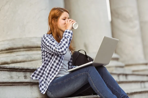 Kvinna dricker kaffe och använder bärbar dator utanför — Stockfoto