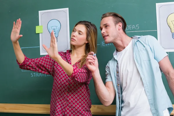 Creative business people at work against blackboard — Stock Photo, Image