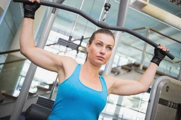 Fit brunette using weights machine for arms — Stock Photo, Image