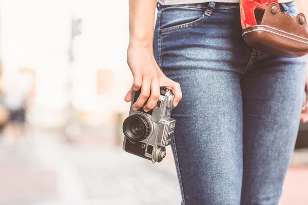 Acercamiento de una chica vistiendo jeans y sosteniendo una cámara — Foto de Stock