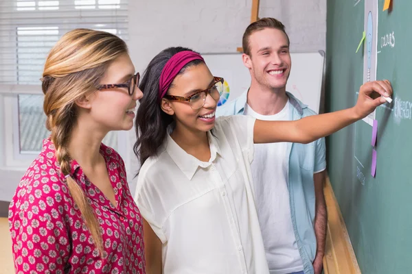 Creative business people at work by blackboard — Stock Photo, Image