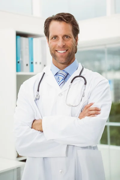 Male doctor with arms crossed in medical office — Stock Photo, Image