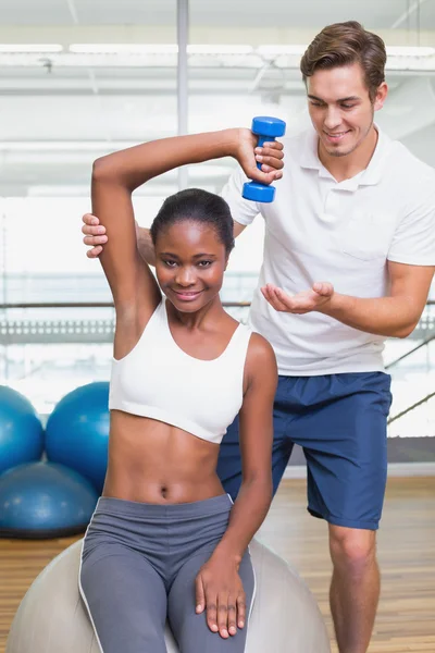 Personal trainer helping client lift dumbbell — Stock Photo, Image