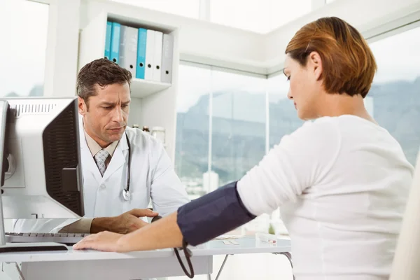 Médico verificando a pressão arterial da mulher no consultório médico — Fotografia de Stock