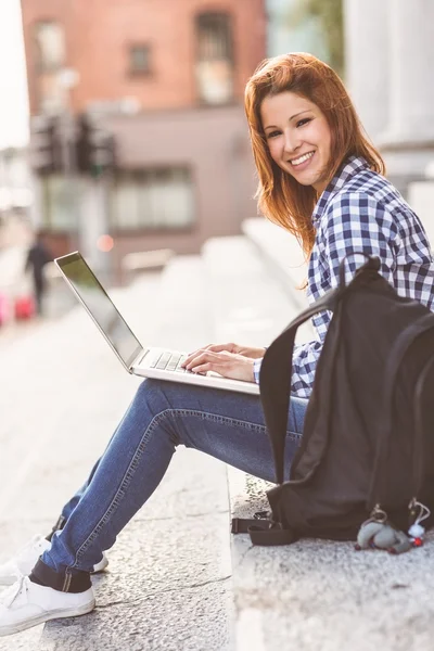 Προσωπογραφία γυναίκας χρησιμοποιώντας το laptop και να χαμογελά στη φωτογραφική μηχανή — Φωτογραφία Αρχείου