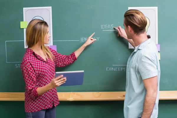 Kreative Geschäftsleute mit digitalem Tablet an der Tafel — Stockfoto