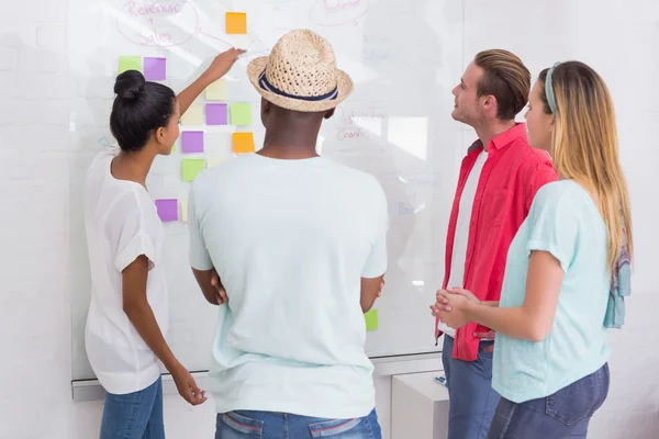 Creative team clapping hands by sticky notes on wall — Stock Photo, Image
