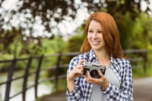 Kvinna som bär jeans och check skjorta innehar kamera — Stockfoto