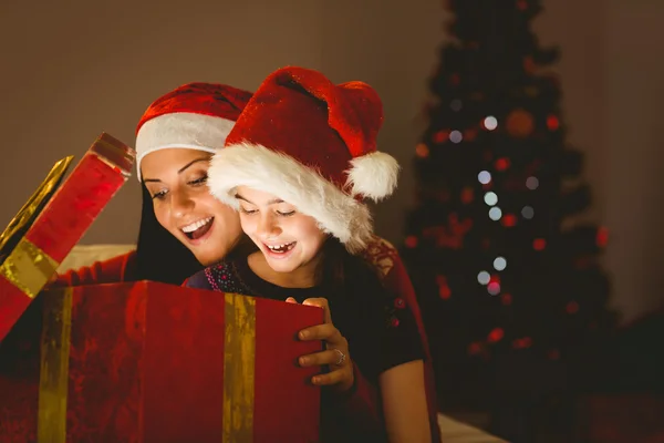 Madre e hija festiva abriendo un brillante regalo de Navidad —  Fotos de Stock