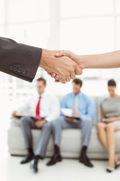 Handshake kromě lidi čekající na rozhovor — Stock fotografie