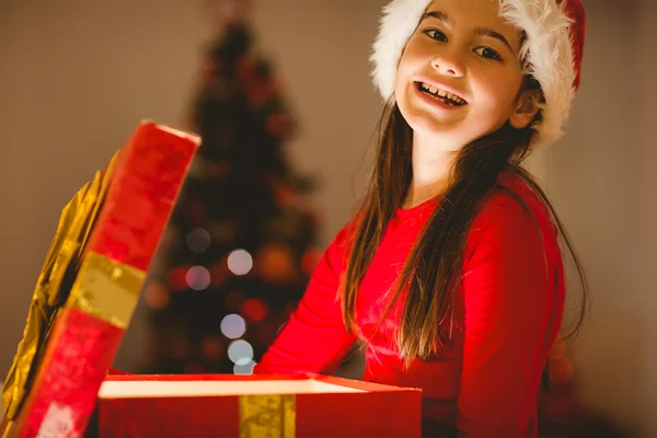 Festliches kleines Mädchen öffnet ein leuchtendes Weihnachtsgeschenk — Stockfoto