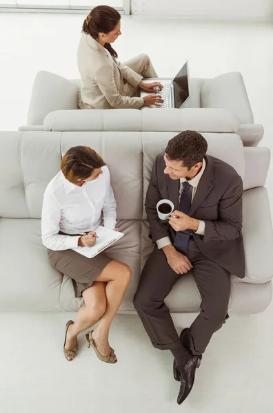 Young business people on couch — Stock Photo, Image