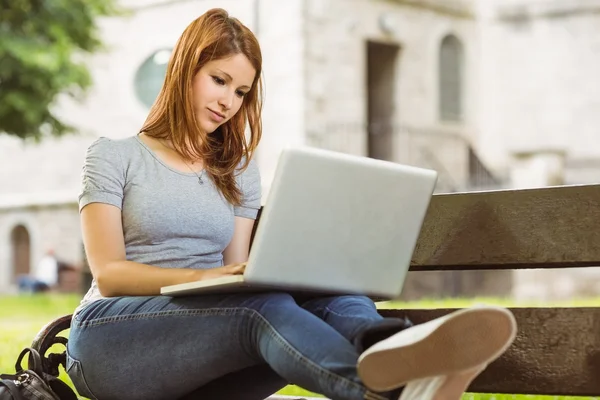 Happy girl sitting on bench using laptop — Stock Photo, Image