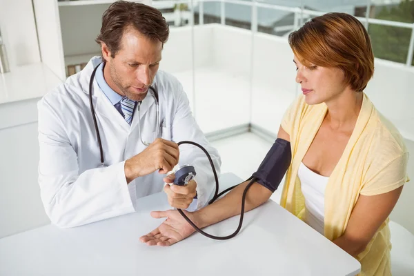 Médico revisando la presión arterial de la mujer en el consultorio médico — Foto de Stock