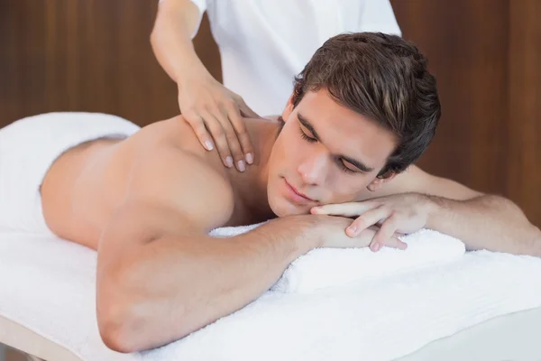 Молодой человек получает массаж плеч в спа-центре — стоковое фото