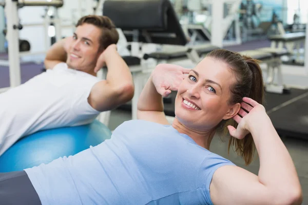 Couple doing sit ups on exercise balls — Stock Photo, Image