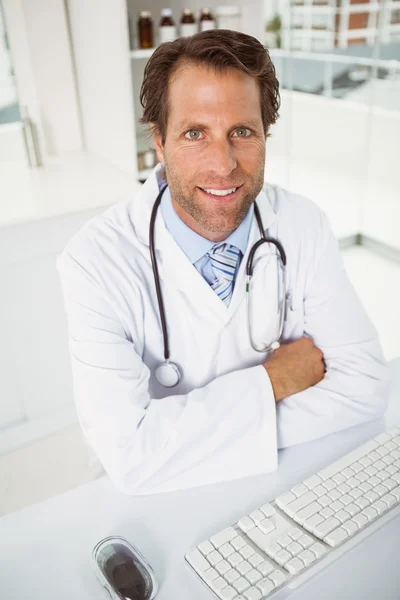 Улыбающийся врач, сидящий в медицинском кабинете — стоковое фото
