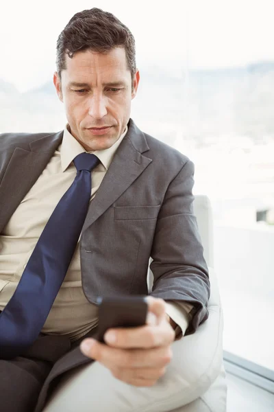 Mensajería de texto de hombre de negocios en la sala de estar — Foto de Stock