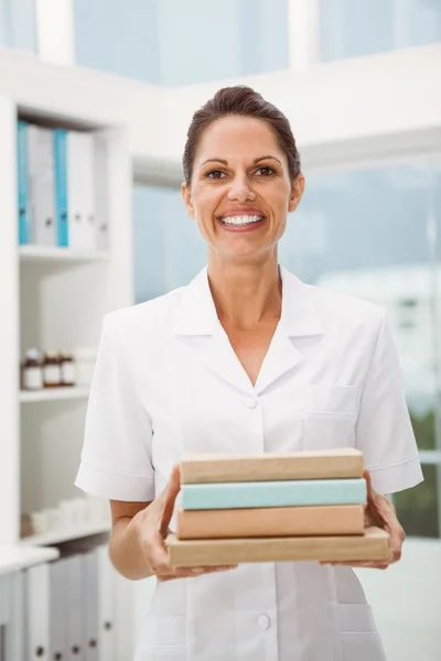 Sorrindo médico feminino segurando livros em consultório médico — Fotografia de Stock