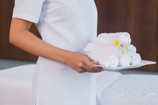 Mid section of masseur holding rolled up towels — Stock Photo, Image