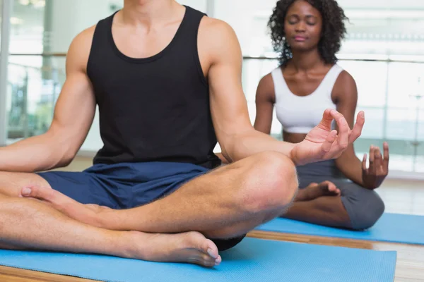 Couple assis dans la pose de lotus dans un studio de fitness — Photo