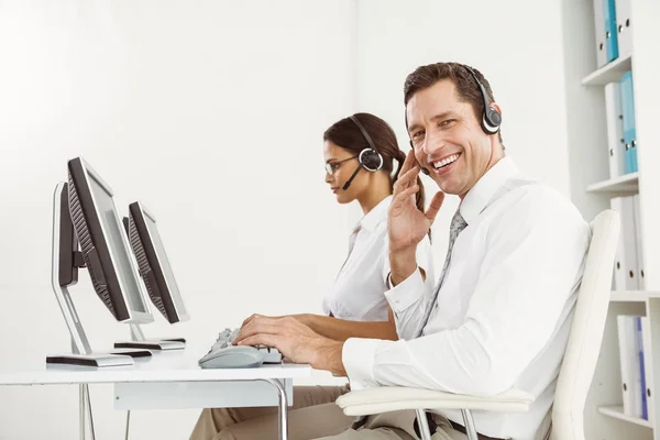 Affärsmän med headset använder datorer i office — Stockfoto
