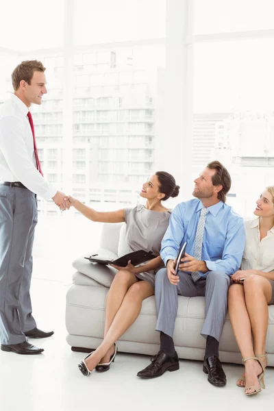 Businessman shaking hands with woman besides people waiting for interview — Stock Photo, Image