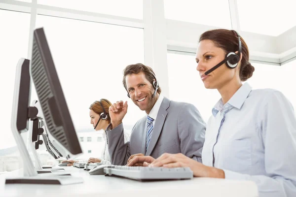 Gente de negocios con auriculares usando computadoras en la oficina —  Fotos de Stock