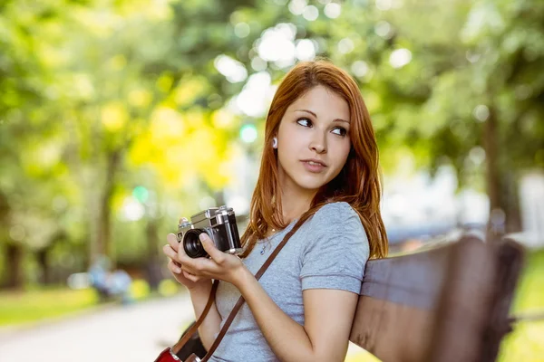 赤毛の彼女のカメラを使用してのベンチに座って — ストック写真