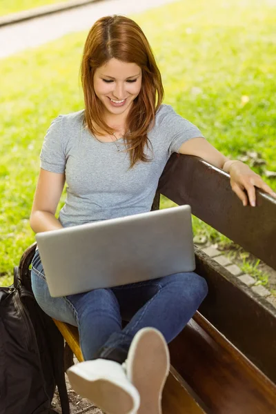 Söt flicka sitter på bänken med laptop — Stockfoto