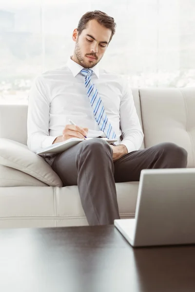 Zakenman schrijven nota's in woonkamer — Stockfoto